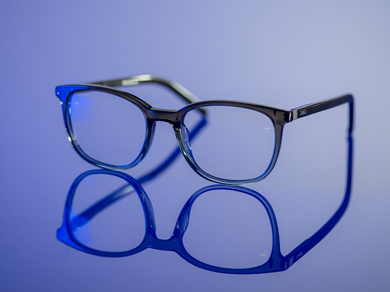 Lentes transparentes con prescripción sobre una superficie azul brillante.