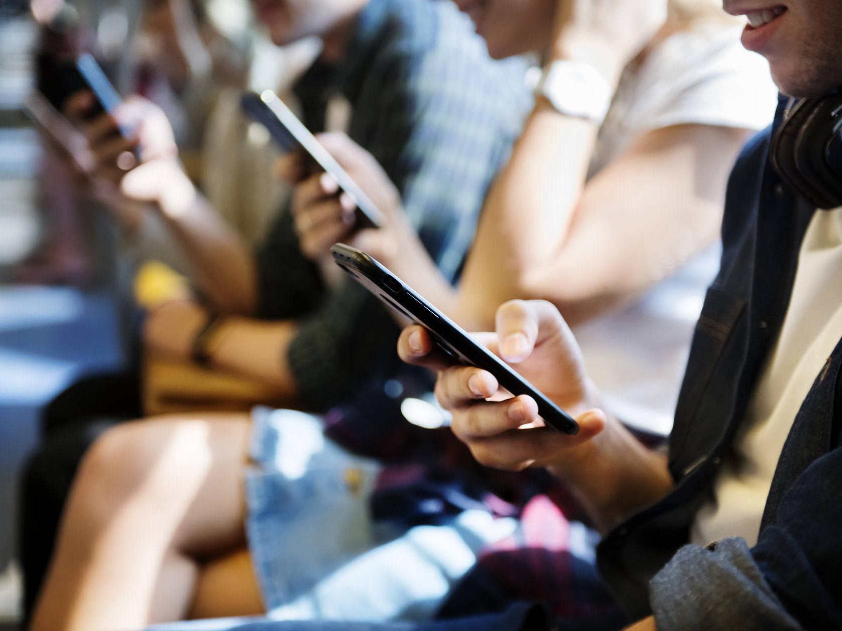 Los teléfonos inteligentes emiten niveles altos de luz azul. Imagen con muchas personas mirando sus teléfonos inteligentes. 