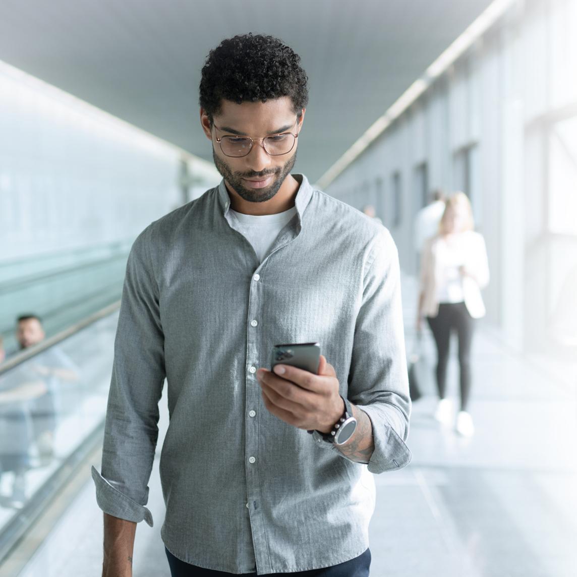 Un joven con los lentes ZEISS SmartLife consulta su teléfono mientras va caminando.