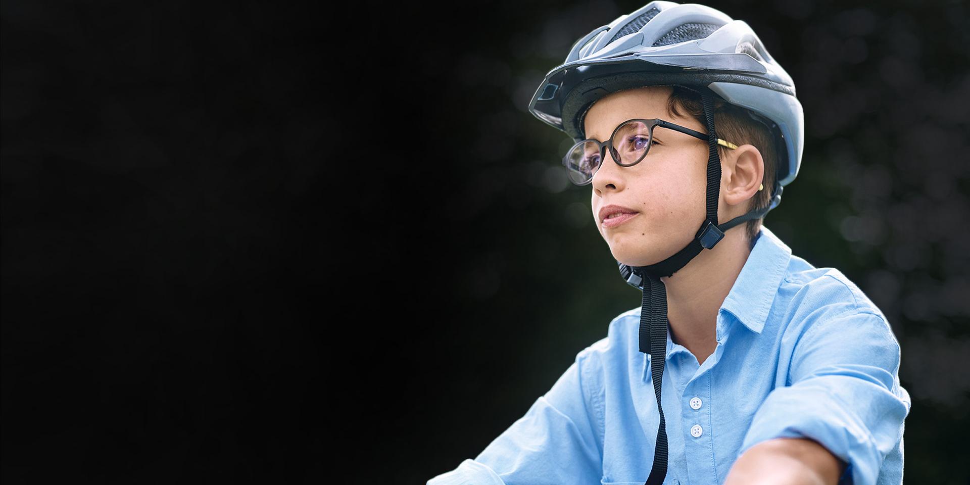 Joven con lentes y un casco aparece montando en bicicleta.