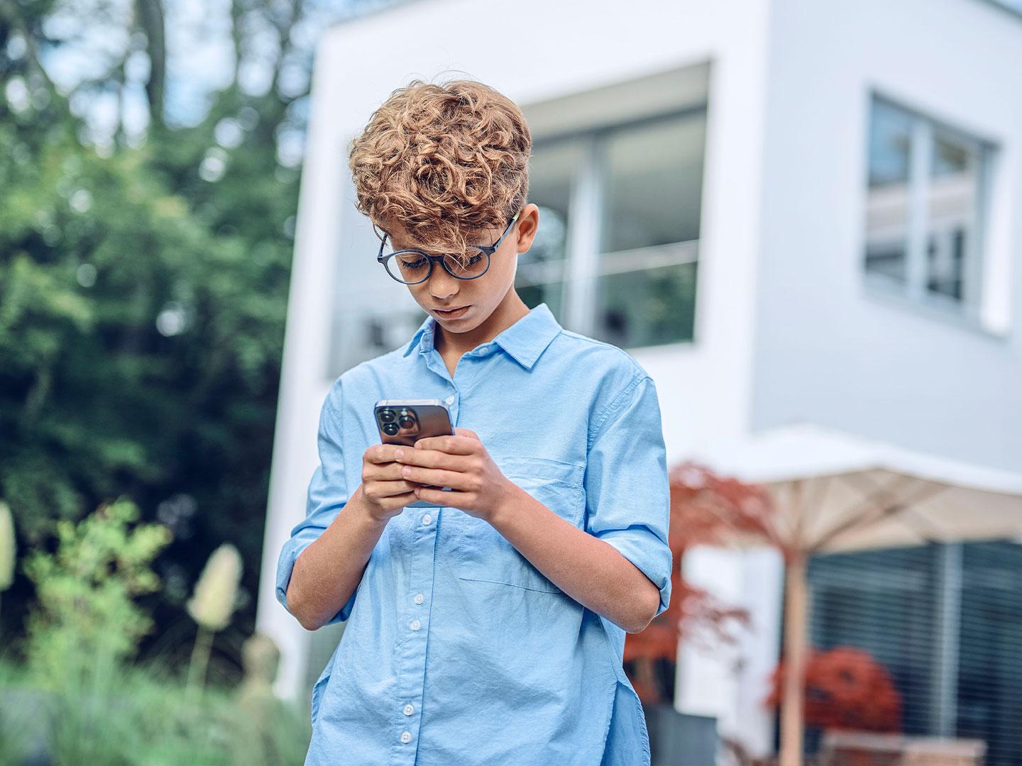Joven, afuera, mirando su teléfono.