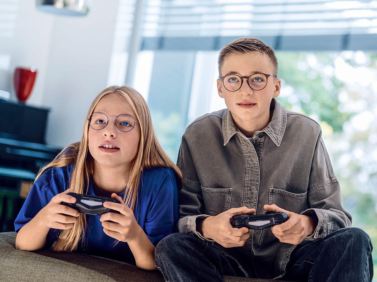 Dos adolescentes jugando video juegos con consolas.