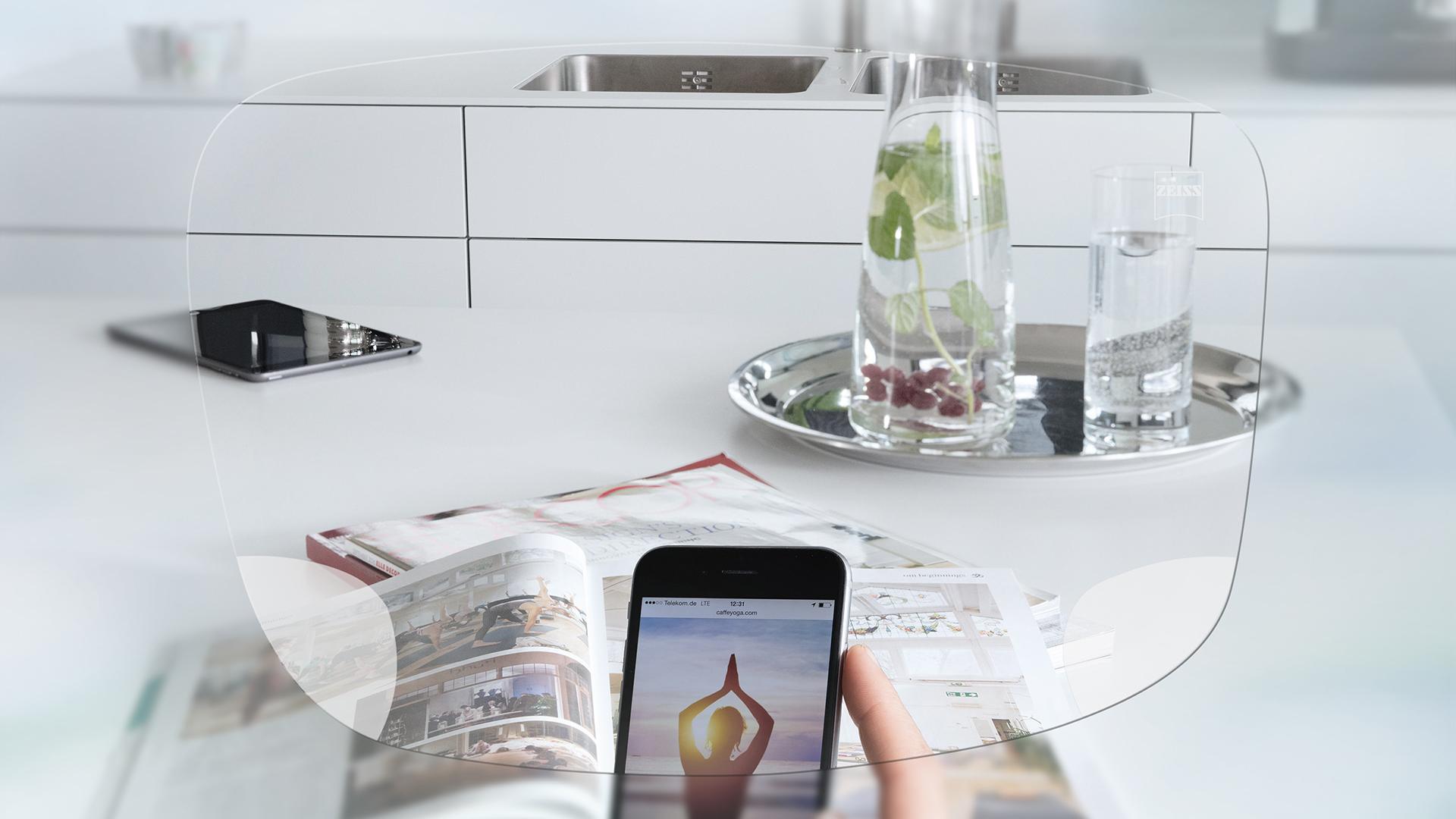 Vista a través de un lente de visión sencilla ZEISS EnergizeMe de la pantalla de un teléfono móvil y una mesa de cocina