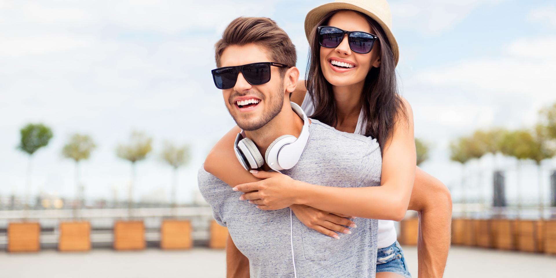 Hombre llevando a su sonriente novia a la espalda