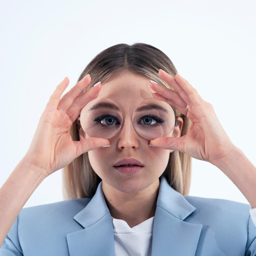 Una joven sostiene dos lentes gruesos delante de los ojos para mostrar el efecto pecera.