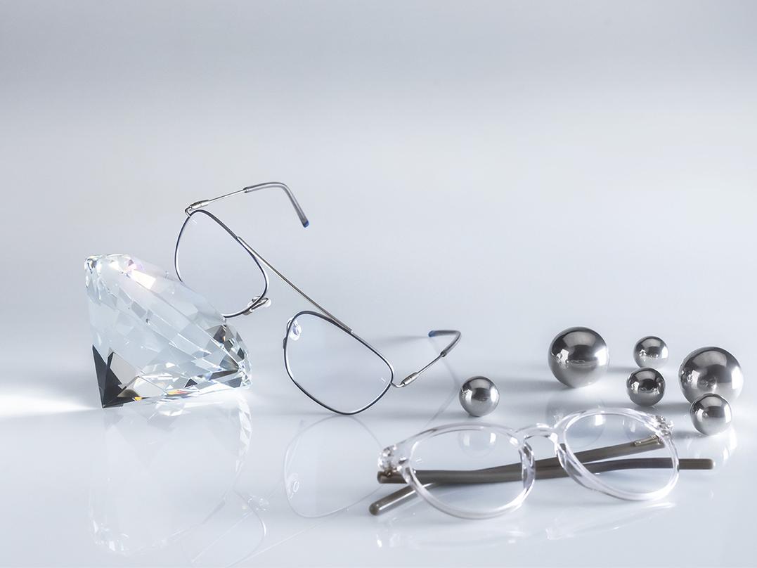 Dos pares de lentes ZEISS recubiertos con el protector DuraVision® AntiVirus Platinum más duro e higiénico que se conoce. Un par de lentes apoyado en un cristal, el otro yace en el suelo junto a la plata. Ambas tienen lentes transparentes sin reflejos azulados. 