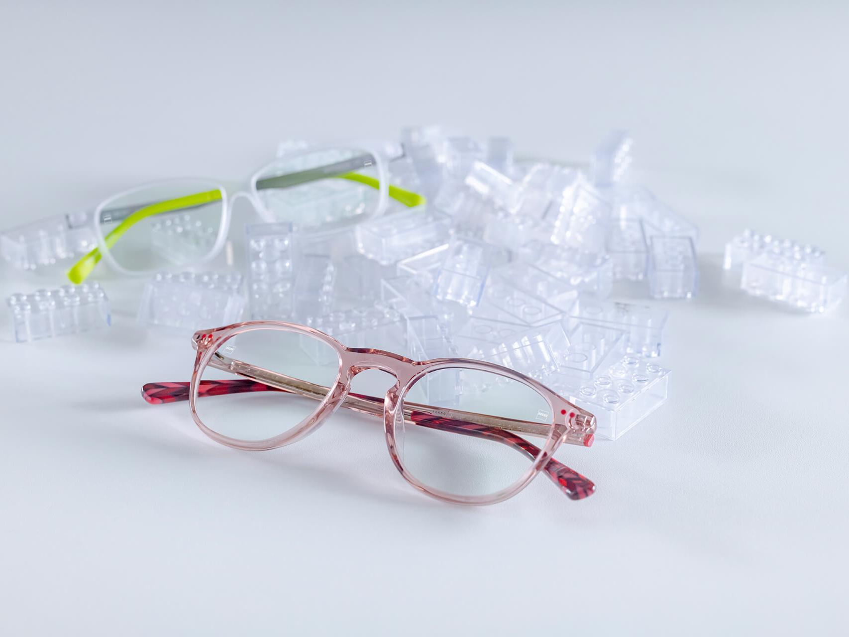 Dos pares de lentes infantiles con lentes ZEISS y recubrimientos DuraVision® para niños. Los lentes se colocan entre ladrillos infantiles transparentes.