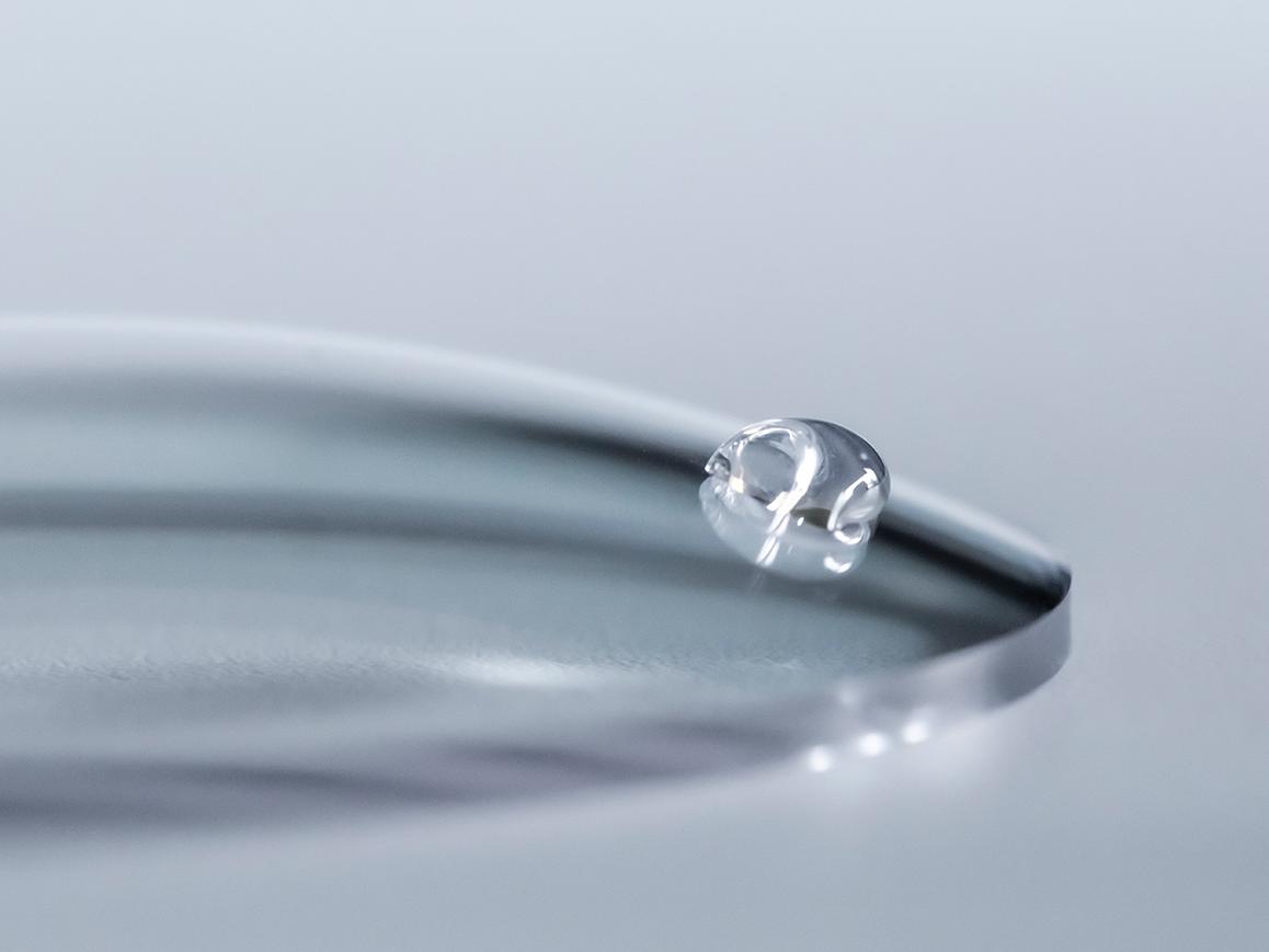 Una gota de agua se desliza por un lente ZEISS con un recubrimiento de limpieza fácil.