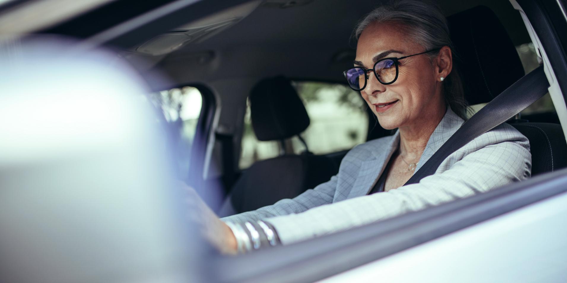 Una mujer madura en un vehículo usa lentes ZEISS DriveSafe.