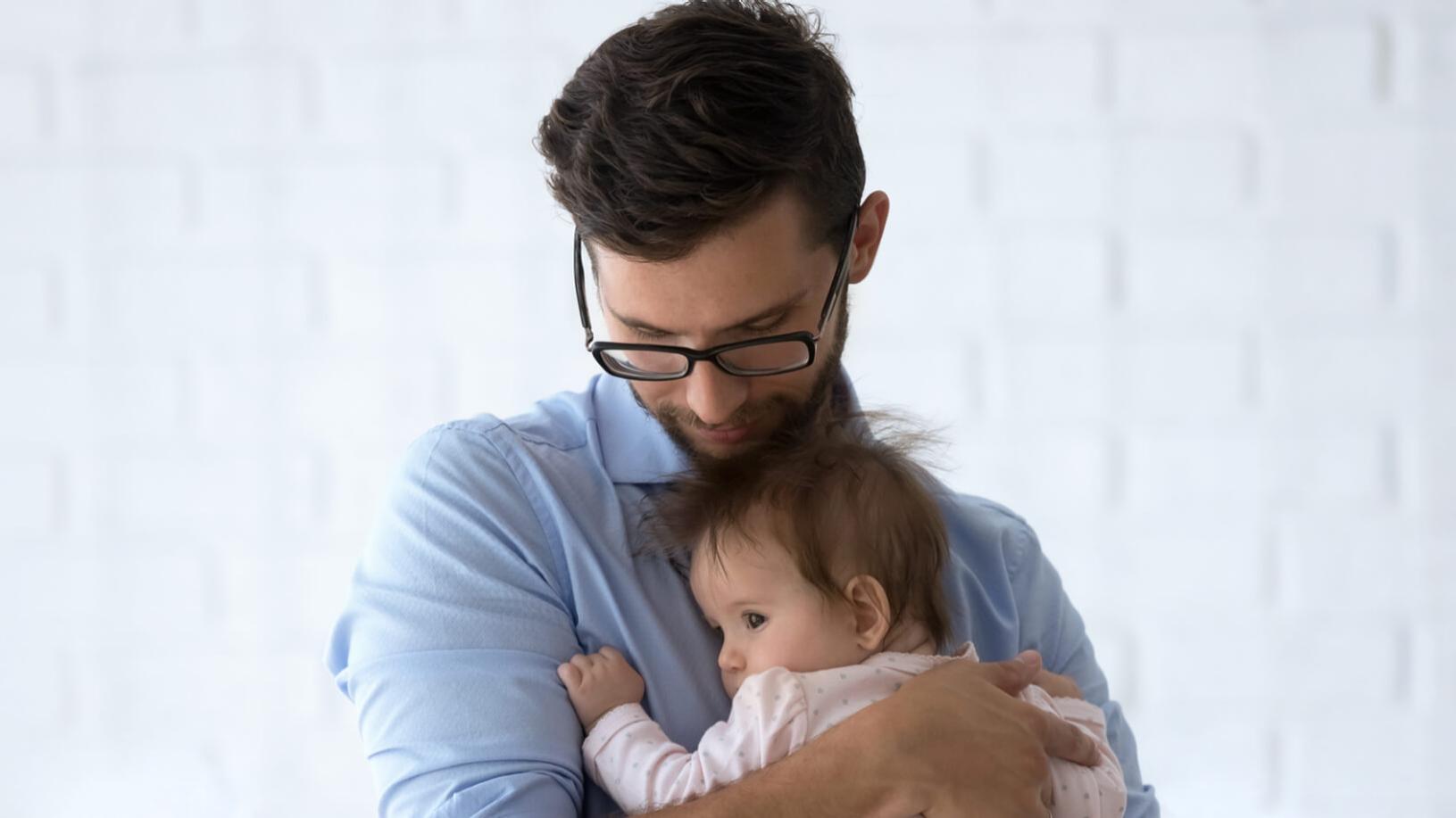 Un hombre miope con lentes sujetando a un niño pequeño.