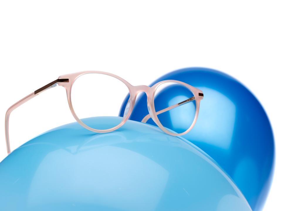 Montura de cristales rosa con lentes con prescripción ZEISS MyoCare en un globo azul.