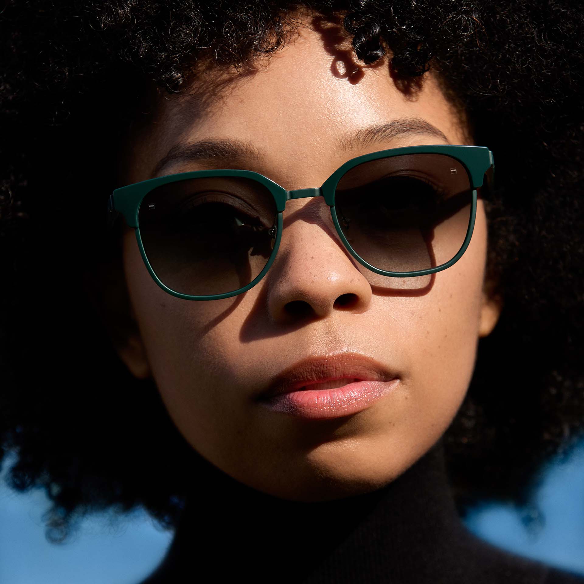 Una mujer con una montura verde y lentes con gradiente de color. 