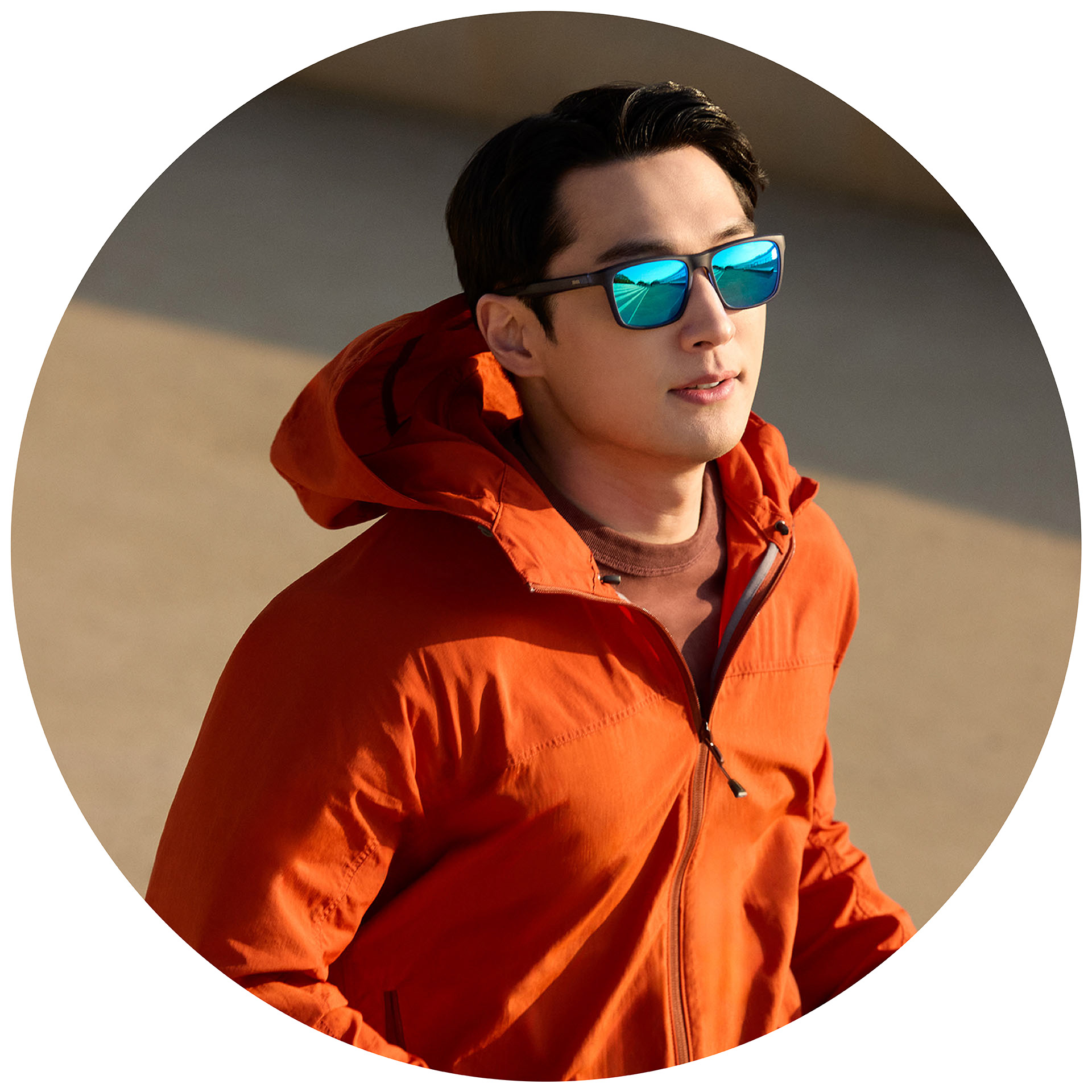 Una persona corriendo con una chaqueta naranja y lentes graduados para gafas de sol ZEISS con protector espejado azul.