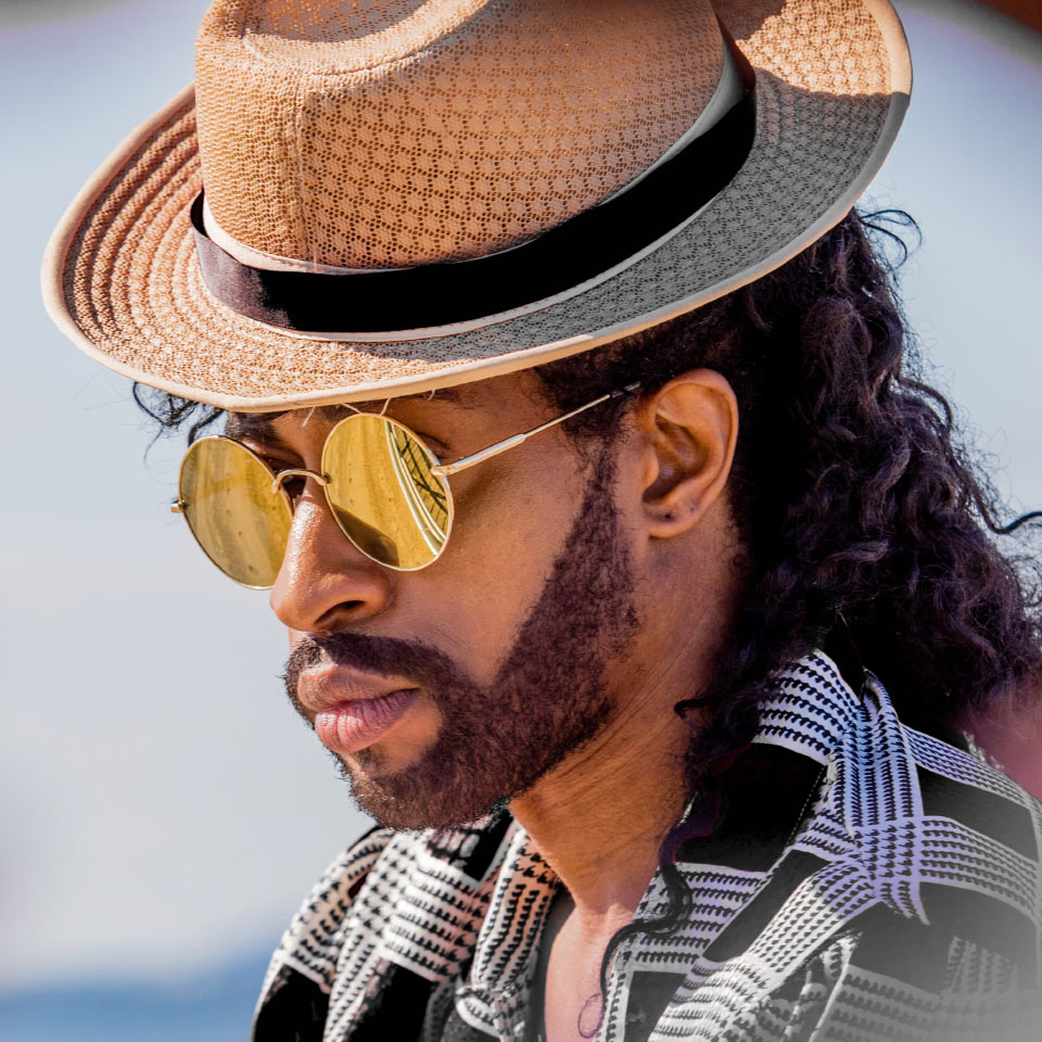 Un hombre en la playa con lentes de sol espejadas en dorado.
