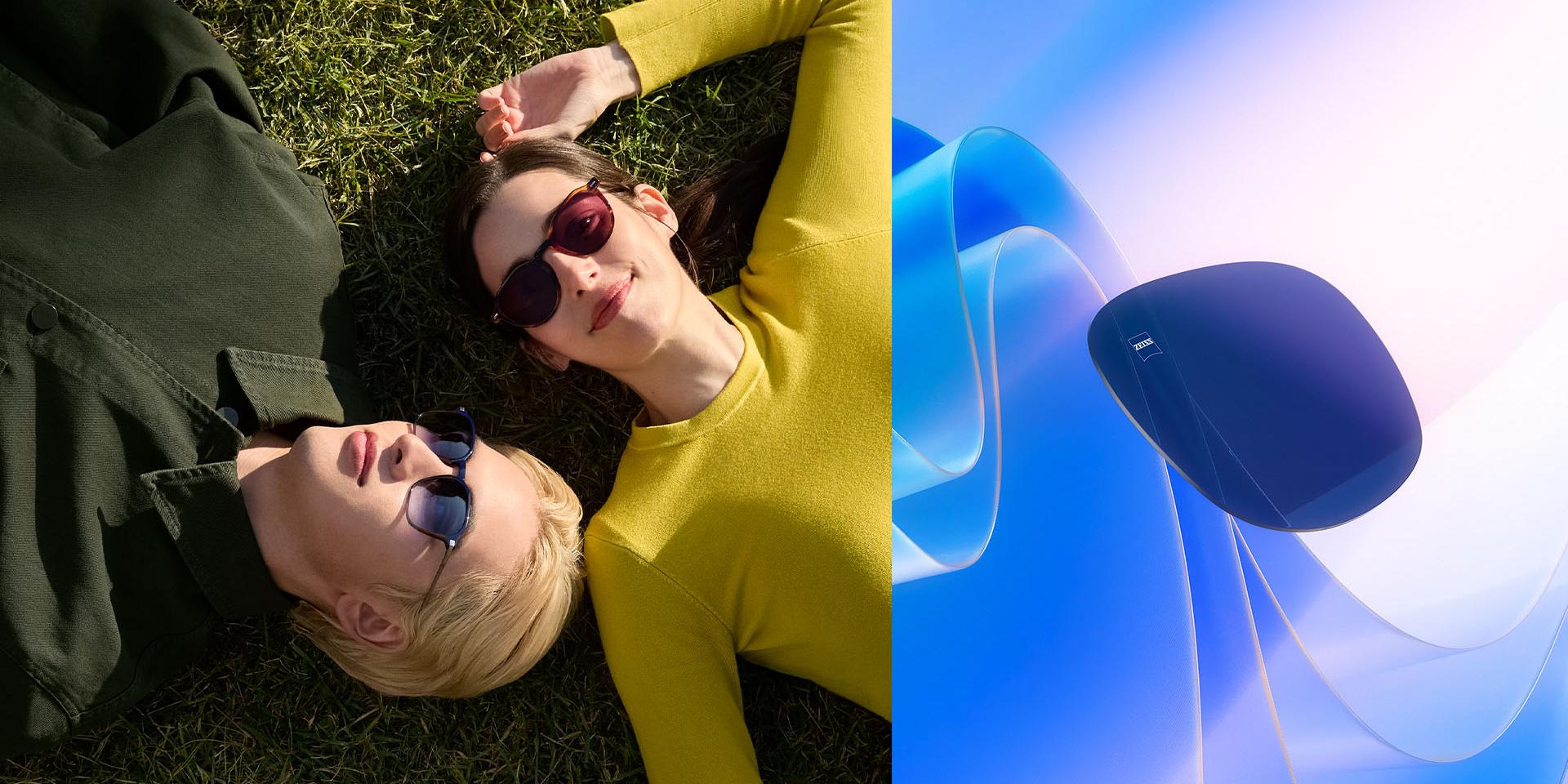 Hombre y mujer con lentes graduados para gafas de sol ZEISS, relajados en la hierba mirando al cielo. Se muestra una representación por CGI de un lente tintado flotando hacia la luz del sol, lo que ilustra su capacidad para bloquear los rayos UV