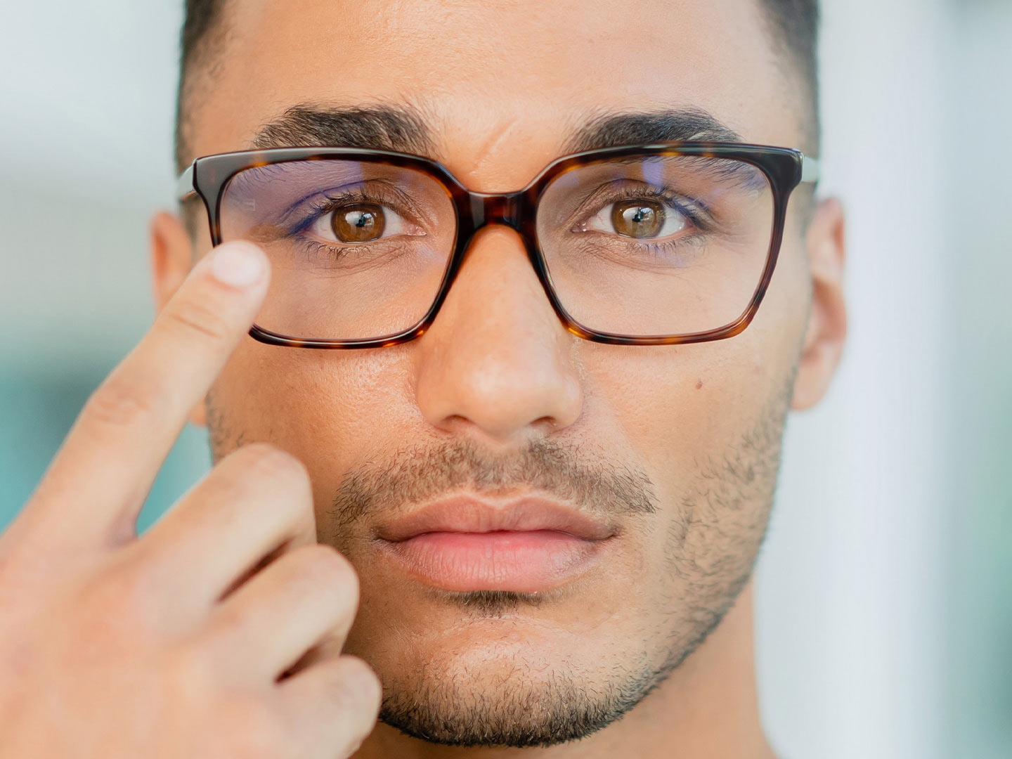 Un hombre con gafas tocando la superficie de sus lentes