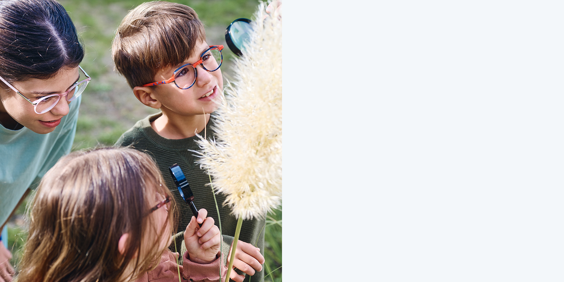 Dos niñas y un niño con lentes MyoCare de ZEISS. Están mirando una planta, dos de los tres niños miran la planta usando lupas.