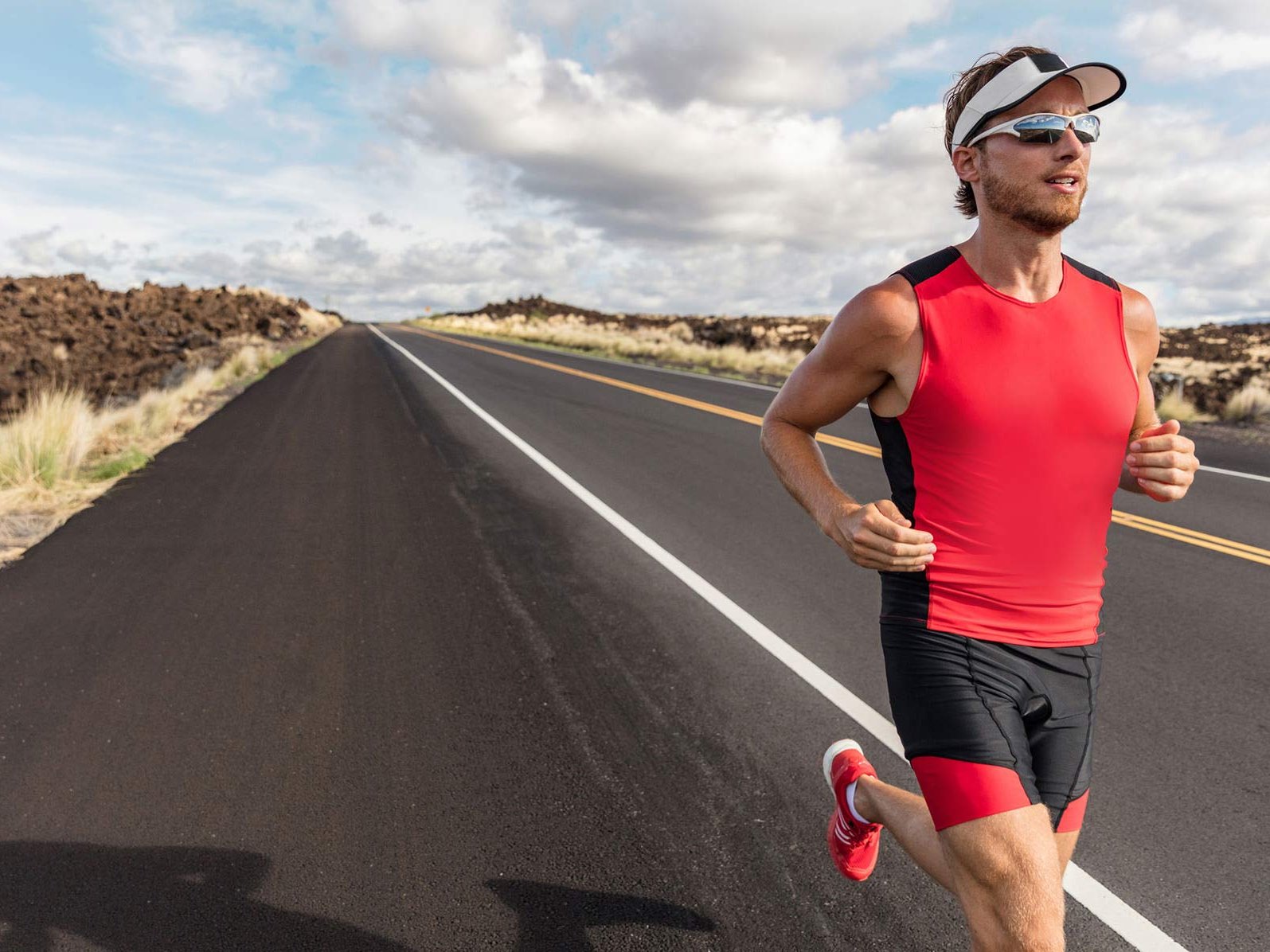 Imagen de un hombre con ropa deportiva y lentes deportivos mientras circula por una carretera. 