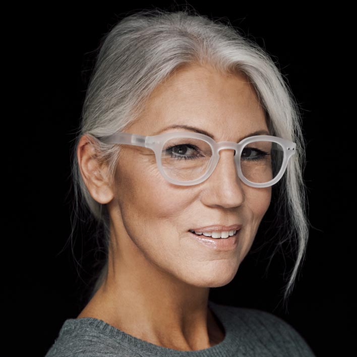Mujer de pelo gris con montura blanca usando lentes progresivos ZEISS SmartLife. Escaneado geométrico del rostro que muestra la anatomía facial y las medidas de la montura.